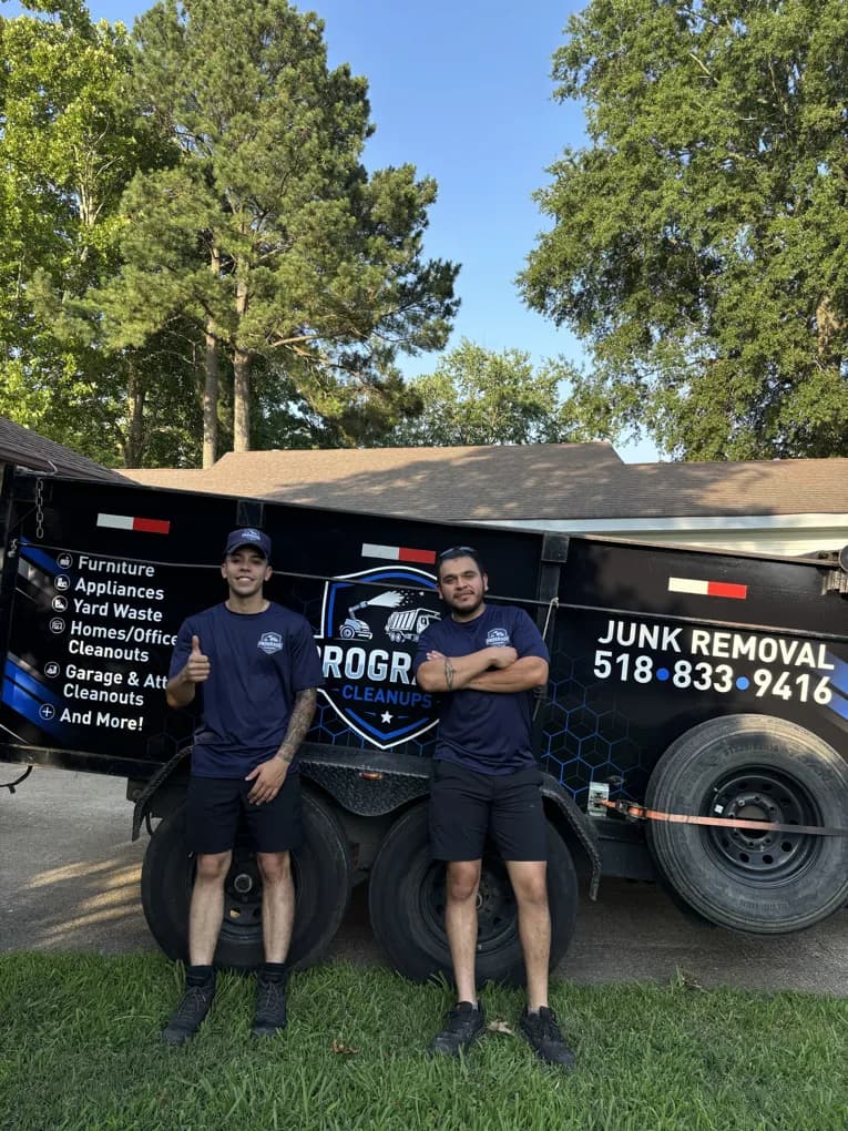 Two members of the ProGrade Cleanups crew in front of the company's junk removal trailer