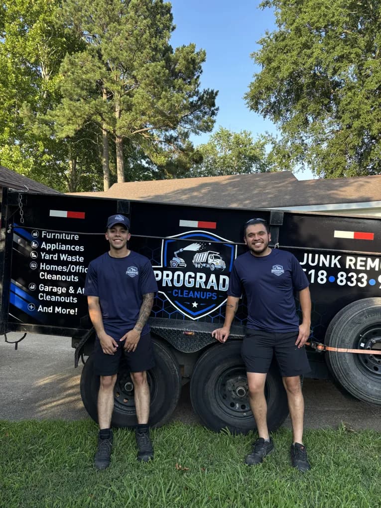 ProGrade Cleanups crew standing by the branded trailer listing furniture, appliances, yard waste and cleanouts